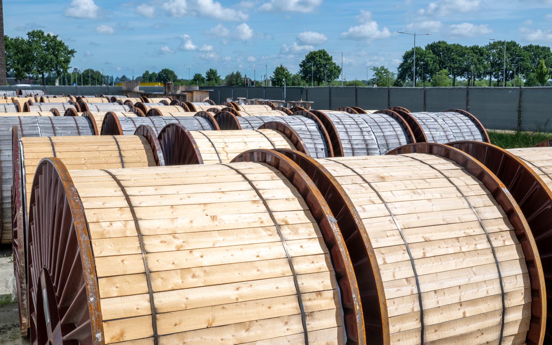 Rows of large wooden cable drums in an outdoor storage yard