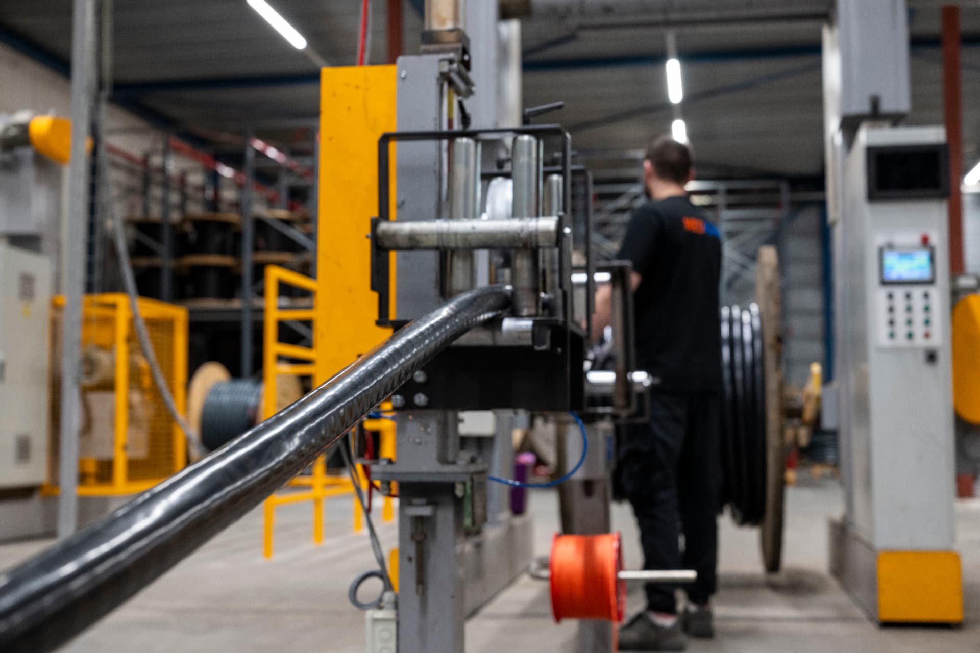 A colleague operating equipment as electrical cable passes through factory rollers