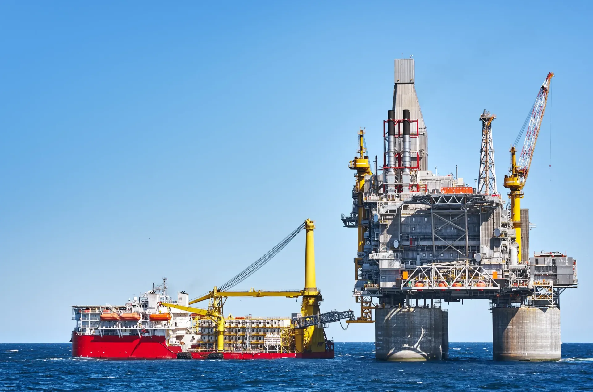 An offshore drilling platform and support vessel at sea